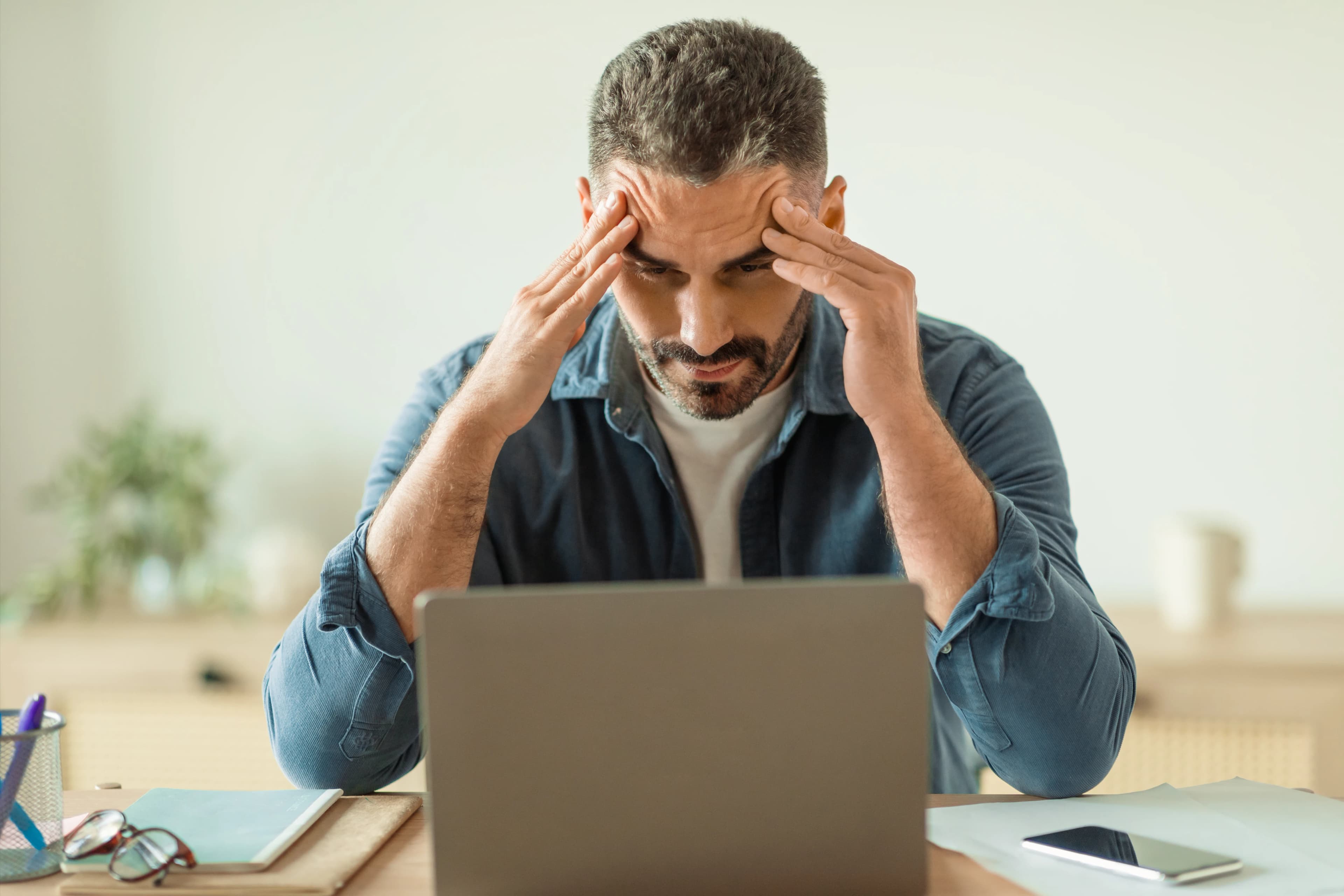 Imprenditore stressato con le mani sulla testa davanti al laptop